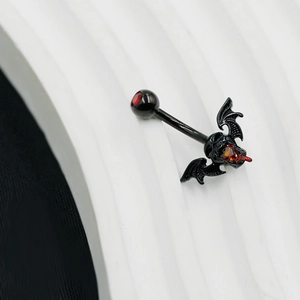 Macro detail of black gothic navel ring with skull, bat wings and red heart zircon