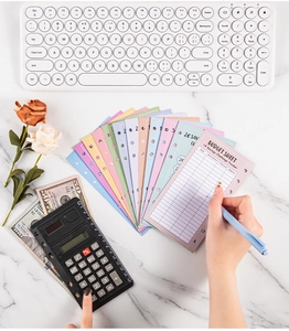 Flat lay of colorful A6 savings challenge budget sheets with calculator and keyboard