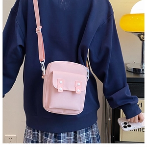 Pink canvas crossbody bag featuring a front flap pocket and adjustable shoulder strap