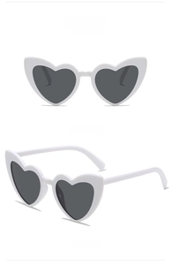 Detailed views of white heart-shaped sunglasses with grey lenses in front and side angles