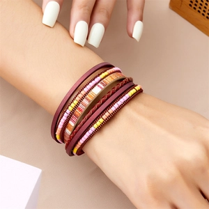 Gros plan d'un bracelet de style bohème en cuir multicouche avec perles rouges sur le poignet