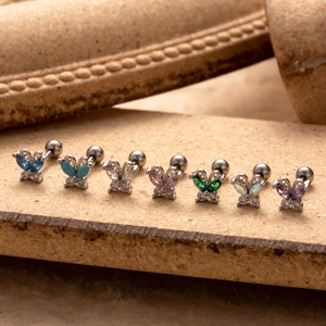 Stainless steel butterfly stud earrings set with colorful zircon stones on stone background