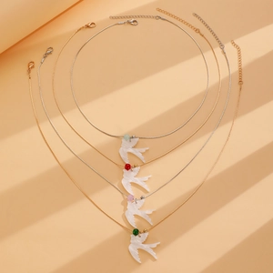 Détail de colliers pendentifs oiseaux en nacre avec perles colorées sur chaîne dorée
