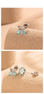Macro detail of cherry-shaped cartilage earring with blue zircons and bow design