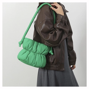 Detail view of green cloud puffer bag with knotted strap worn by a model