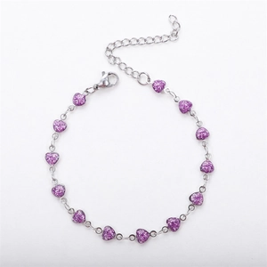 Macro shot of silver metal chain bracelet featuring purple glitter heart charms and clasp