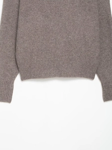 Detail of brown v-neck knit sweater showing ribbed cuffs and soft woolen texture