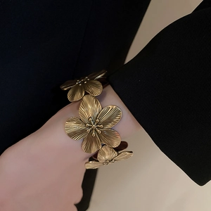 Macro shot of vintage gold flower cuff bracelet with detailed petal texture and engravings