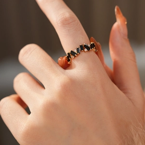 Close-up of a gold ring with black zircon and small diamonds on a model's finger
