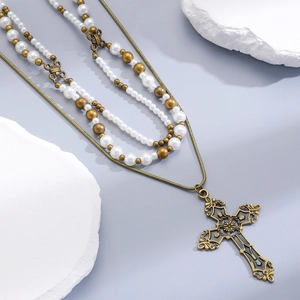 Macro detail of triple-layer vintage cross necklace with pearls and antique bronze finish