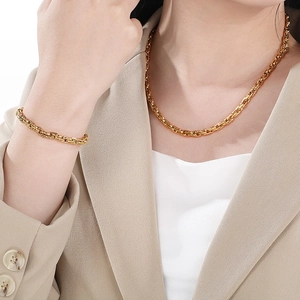 Close-up of a gold-plated twisted cable chain necklace and bracelet set on a model