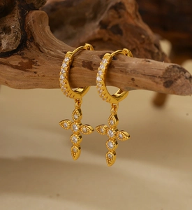 Detail of vintage gold cross earrings with sparkling crystals hanging on a branch
