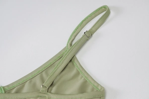 Detail of light green ribbed knit top featuring an adjustable metal strap buckle