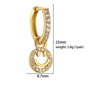 Golden smiley face drop earrings with cubic zirconia inlay on white background