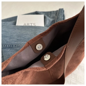 Detail shot of the magnetic snap closures and purple fabric lining on a brown velvet tote