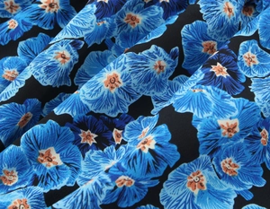 Detail eines blau-orangefarbenen Ink-Wash-Blumendrucks auf weichem, plissiertem Stoff