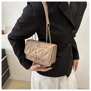 Detail of beige quilted leather bag featuring gold S-logo and fringe tassel pendant