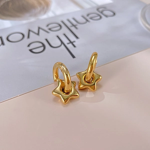 Détail de boucles d'oreilles étoiles dorées polies avec des breloques élégantes