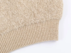 Détail du tissu polaire beige effet peluche et des poignets en tricot côtelé du pull chaud
