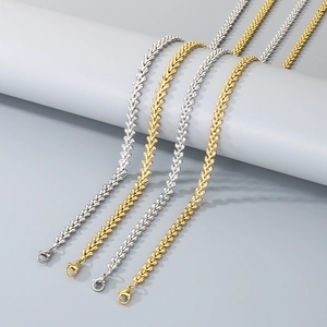 Gold and silver heart-link chain necklaces displayed on minimalist cylindrical props