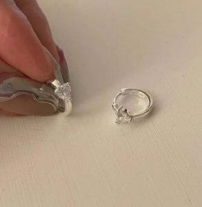 Close-up of S925 silver hoop earrings with sparkling heart-shaped zircon detail