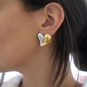Two-tone heart-shaped earrings in 18k gold and silver finish worn by a model