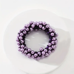 Macro detail of purple pearl hair tie with high elastic black rope on white base