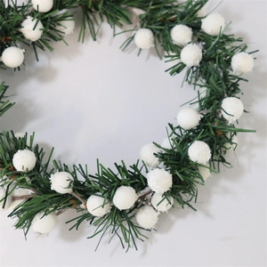 Close-up of green pine needles and white snow berry details on a Christmas candle ring
