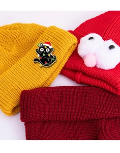 Detail einer Cartoon-Weihnachtskatze-Emaille-Anstecknadel auf gelbem Strickhut
