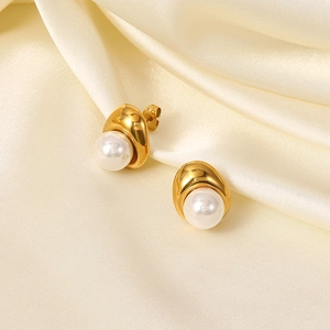 Detail shot of 18K gold plated pearl drop earrings on a soft cream satin background