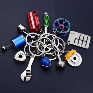 Collection of metal car engine parts and racing helmet keyrings on black background