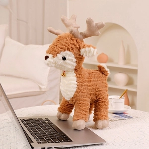 Close-up of a plush deer holiday decoration with golden bell on a laptop keyboard