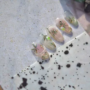 Macro shot of bamboo nail art with gold accents, pearls and soft gradient ink design