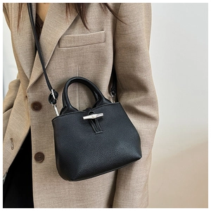 Detail of black lychee grain leather bucket bag with silver bamboo buckle on a model