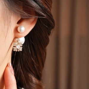 Close-up of model wearing a gold snowflake pendant and pearl earring set with zircons