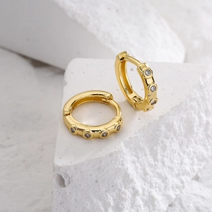 18K gold-plated copper earrings with micro-inlaid zircons on white textured stone