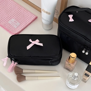 Close-up of black nylon makeup bags with pink bow decor and pearl zipper details