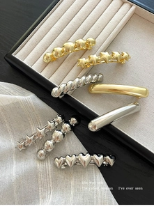 Close-up of gold and silver minimalist metal hair clips on a jewelry tray display