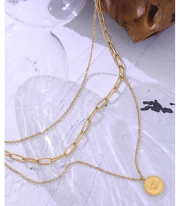 Detail of gold layered necklace featuring a Carpe Diem engraved coin pendant and paperclip chain