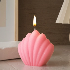 Bougie rose en forme de coquille avec texture nervurée et flamme allumée