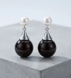 Detailed close-up of elegant black and white contrast pearl drop earrings with silver finish