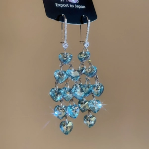 Detailed macro view of heart-shaped blue crystals with multi-layer tassel drop earrings