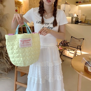 Détail du sac matelassé à cœurs jaune clair avec poignées bleues et doublure violette contrastée