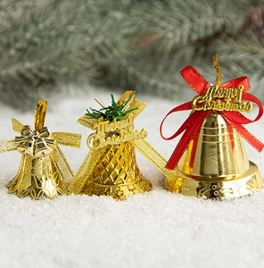 Close-up of golden Christmas bells with glitter bows on snowy pine branch background