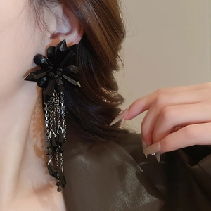 Close-up of black oversized floral tassel earrings with acrylic crystals on model