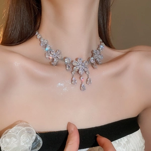 Close-up of sparkling zircon flower necklace with teardrop tassel on model's neck
