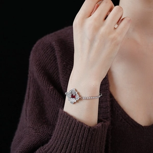 Close-up of a silver bracelet with a red square gemstone in a floral diamond setting