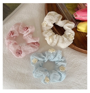 Detailed close-up of pink, white, and blue scrunchies with delicate small rose buds