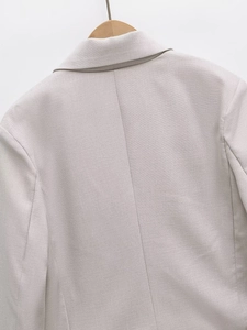 Detail of light gray blazer back seam showing premium textured fabric on wooden hanger