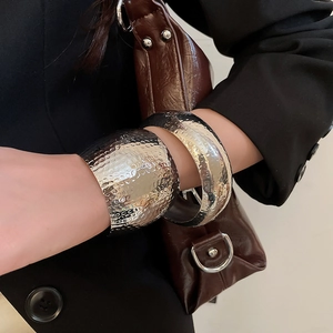 Close-up of stylish wide silver bracelets featuring textured hammer pattern on a model